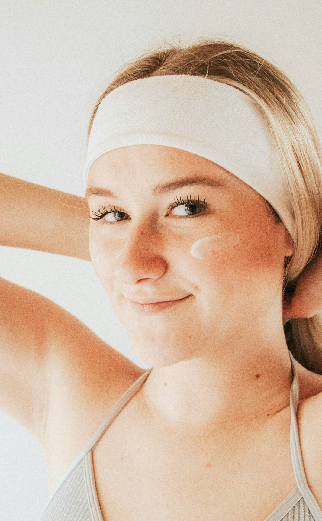 Mujer con diadema aplicando crema facial